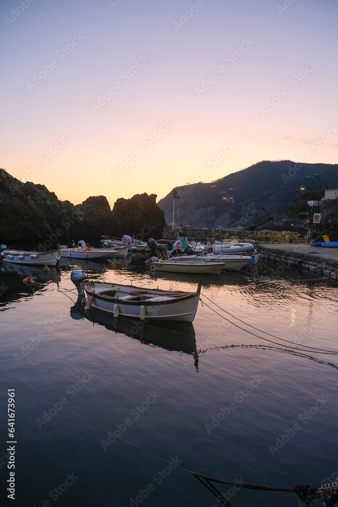 boats in the harbor of Framura, Liguria, Italy during sunset sky across cliffs