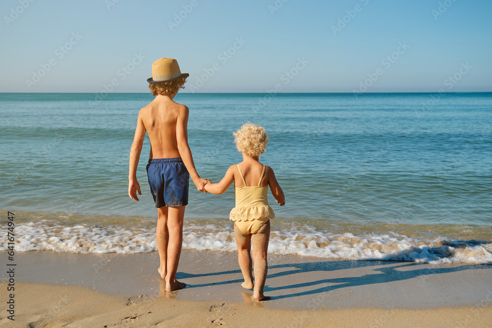 Children holding hands and walking on sandy beach Children holding hands and walking on sandy beach