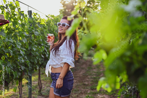 Young beautiful Smiling  italian woman walking at wineyard with a Glass of Red wine.Wine tourism at Tuscany Italy