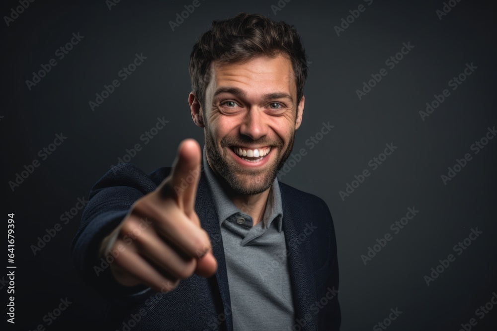 Headshot portrait photography of a happy boy in his 30s pointing with two hands and fingers to the side against a dark grey background. With generative AI technology