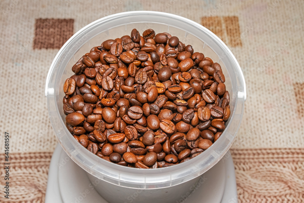 Roasted coffee beans in a plastic container (small bucket) close-up top view Roasted coffee beans in a plastic container (small bucket) close-up top view
