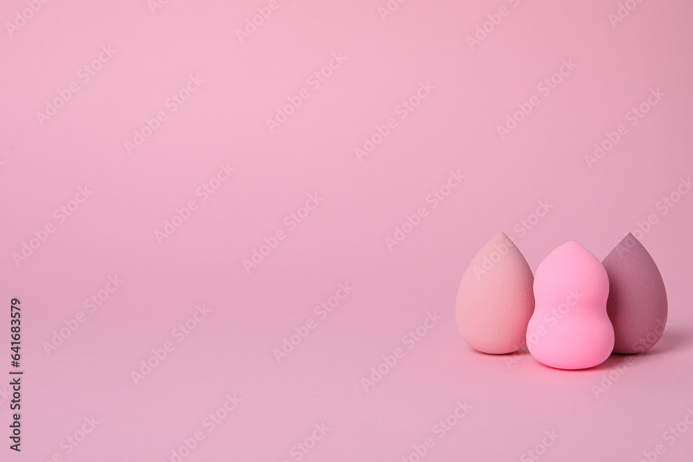 Cosmetic sponges on pink background, space for text