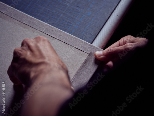 Photography Unrecognizable worker with white fabric and cardboard in bookbinding workshop