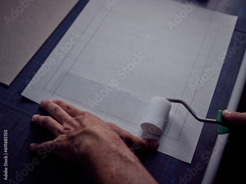 Anonymous bookbinder spreading adhesive substance on marked paper photo