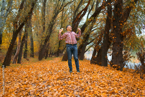 a man walks in a glade by the river bank and enjoys the scenery, beautiful nature in the autumn season, the river and the forest with bright yellow leaves, cloudy sky in the evening