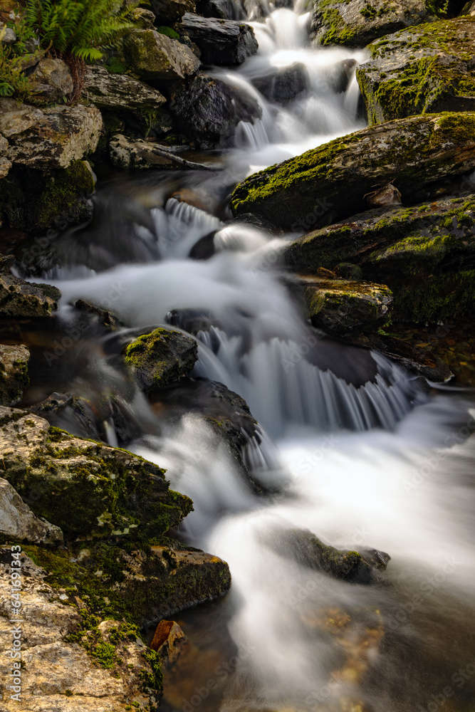 Long exposure image of a cascading mountain stream tumbling over moss covered rocks at Nant Peris, Snowdonia, Llan Beris Pass Wales