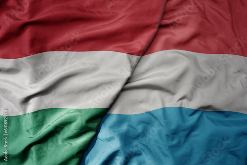 big waving national colorful flag of hungary and national flag of luxembourg .