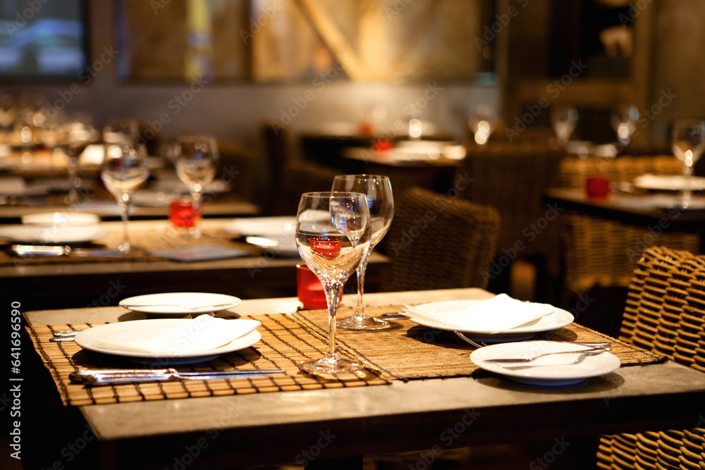 Cozy Restaurant Setting with Rustic Wooden Table Adorned with Plates, Glasses, and Wine: An Invitation to Convivial Gatherings and Culinary Pleasures