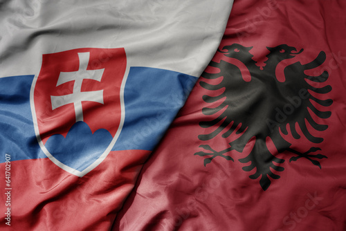 big waving national colorful flag of slovakia and national flag of albania .