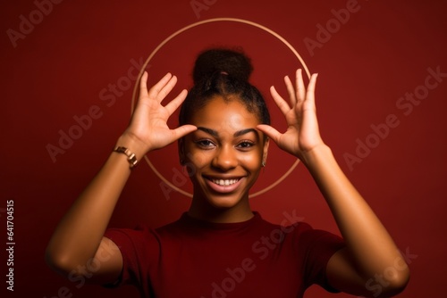 Lifestyle portrait photography of a glad girl in her 20s forming a circle with the fingers to say perfect against a burgundy red background. With generative AI technology