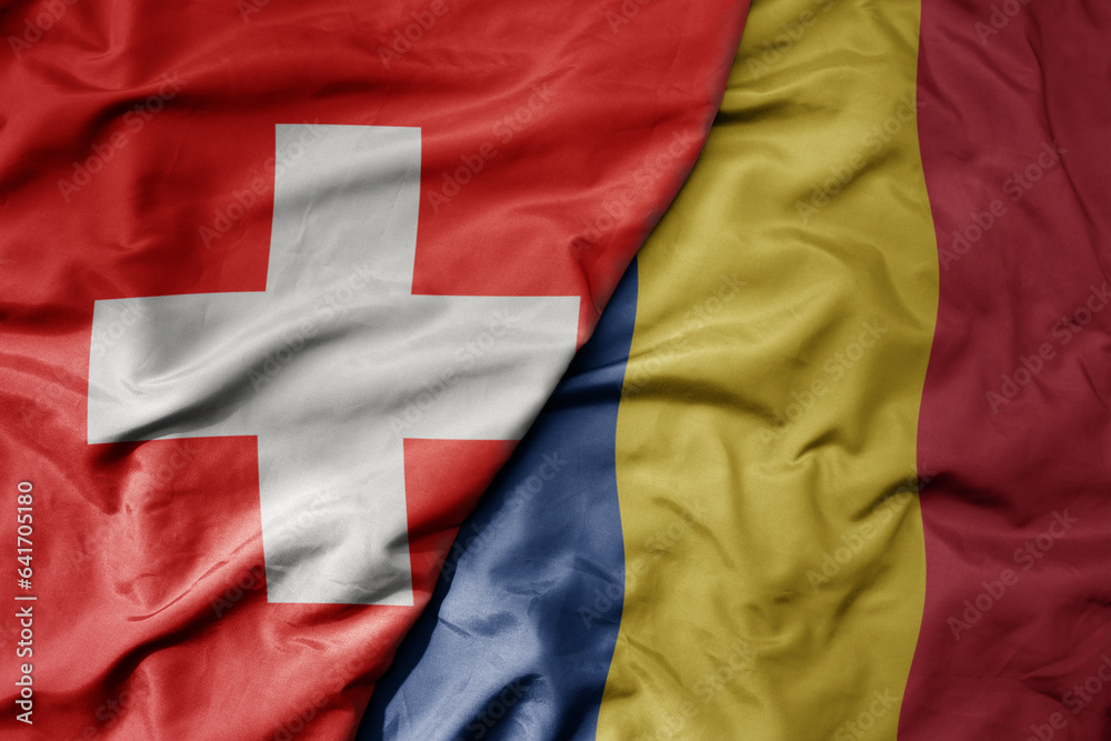 big waving national colorful flag of switzerland and national flag of romania .