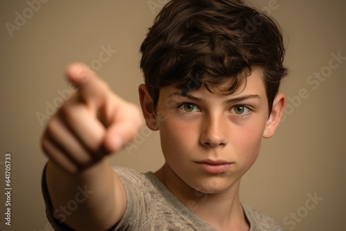 Close-up portrait photography of a tender boy in his 20s pointing empty space against a beige background. With generative AI technology photo