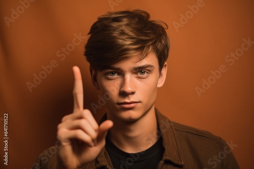 Headshot portrait photography of a tender boy in his 20s making the l sign against a copper brown background. With generative AI technology