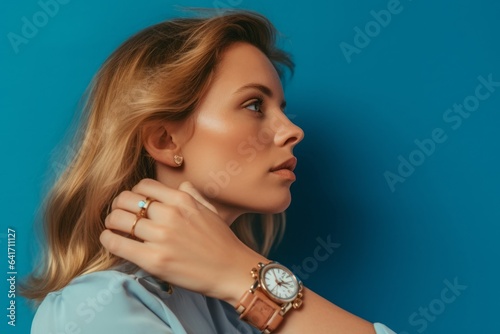 Lifestyle portrait photography of a tender girl in her 30s looking at the time on the watch on his hand against a periwinkle blue background. With generative AI technology