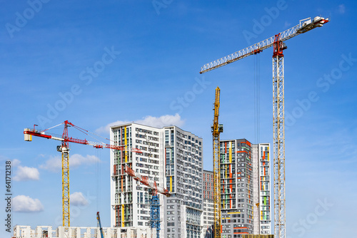 Tower cranes on the construction site of a block of flats of the monolithic residential apartment building	