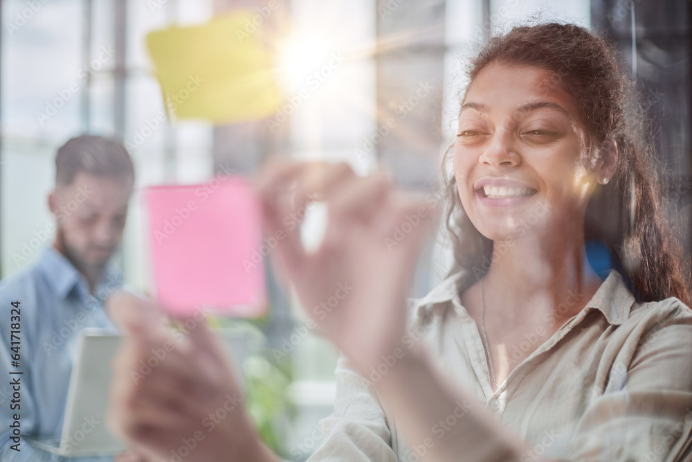 Bringing her vision to life. Shot of a confident businesswoman presenting an idea to her colleague using adhesive notes on a glass wall in the office. Bringing her vision to life. Shot of a confident businesswoman presenting an idea to her colleague using adhesive notes on a glass wall in the office.