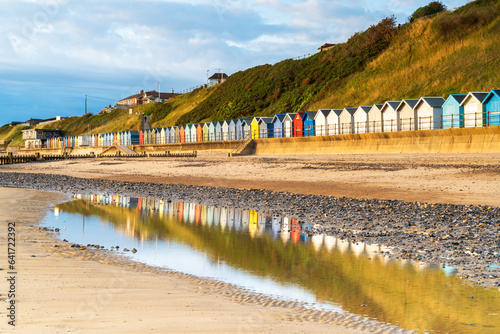 Relections of the beach huts on the beach at Mundesley in North Norfolk, UK at Sunrise photo
