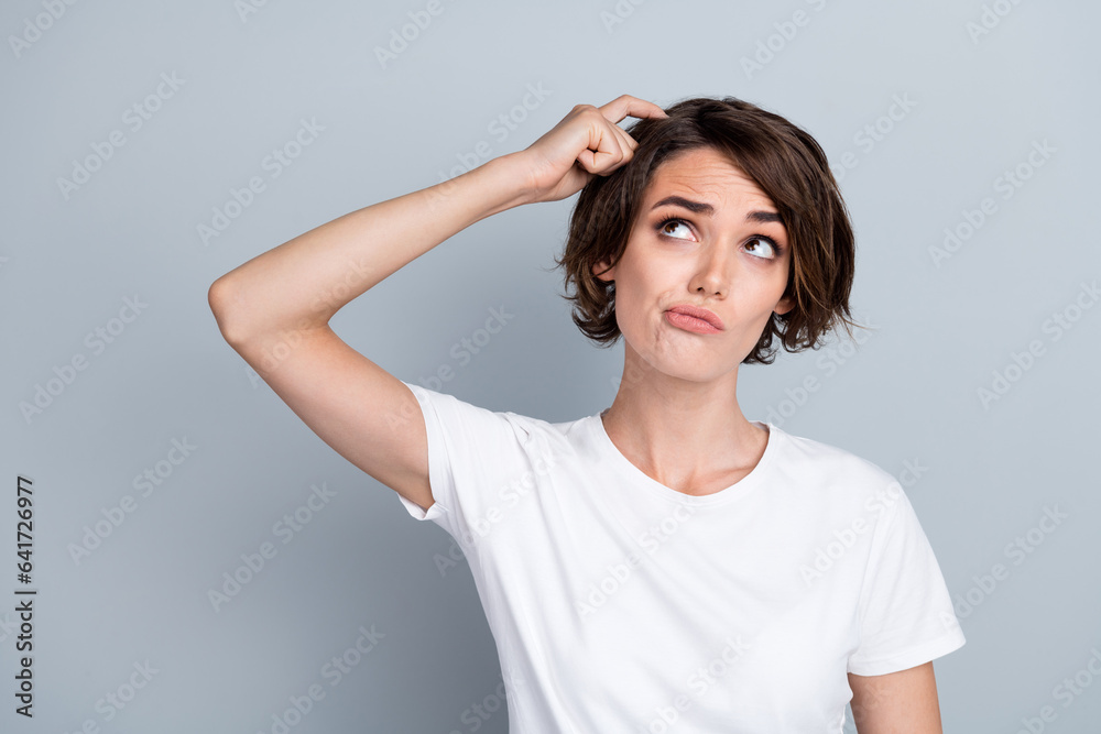 Photo of doubtful unsure lady wear white t-shirt finger head looking empty space isolated grey color background