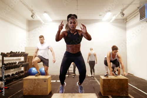 Fit young woman doing box jumps during an exercise class photo