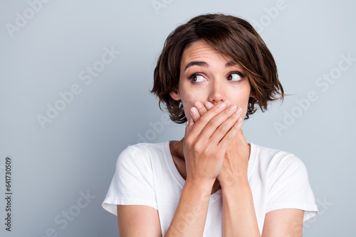 Photo of thoughtful guilty lady wear white t-shirt arms cover lips looking empty space isolated grey color background