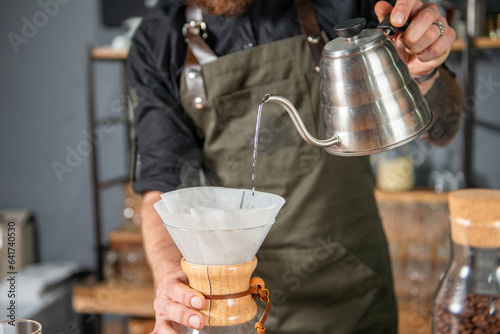 Skillful barista meticulously preparing a Chemex coffee, demonstrating the art of pour-over brewing  photo