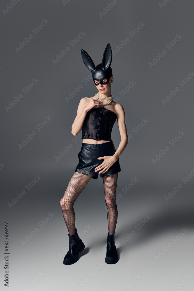 queer person in corset posing in bdsm bunny mask on grey, pearl necklace, provocative fashion queer person in corset posing in bdsm bunny mask on grey, pearl necklace, provocative fashion