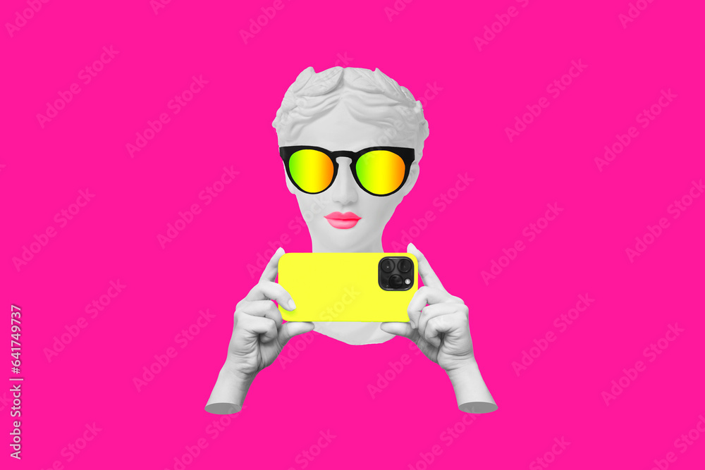 Antique statue's head in sunglasses holding yellow mobile phone with photo camera in hands taking picture on bright pink color background. 3d trendy creative collage. Contemporary art. Modern design Antique statue's head in sunglasses holding yellow mobile phone with photo camera in hands taking picture on bright pink color background. 3d trendy creative collage. Contemporary art. Modern design