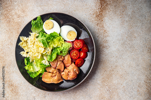 pasta salad chicken liver, tomato, green leaf lettuce, boiled egg, farfalle salad ready to eat meal food snack on the table copy space food background rustic top view