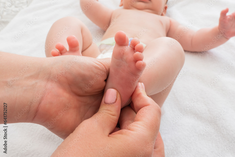 Mother massages the tiny feet of her child, Concept of nurturing touch and care Mother massages the tiny feet of her child, Concept of nurturing touch and care
