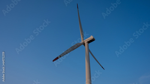 Bottom view of a windmill against a blue sky. Alternative energy source. © Михаил Решетников