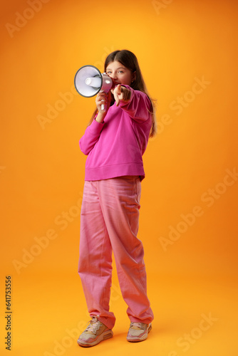 Принти на полотні Teen girl making announcement with megaphone on yellow background