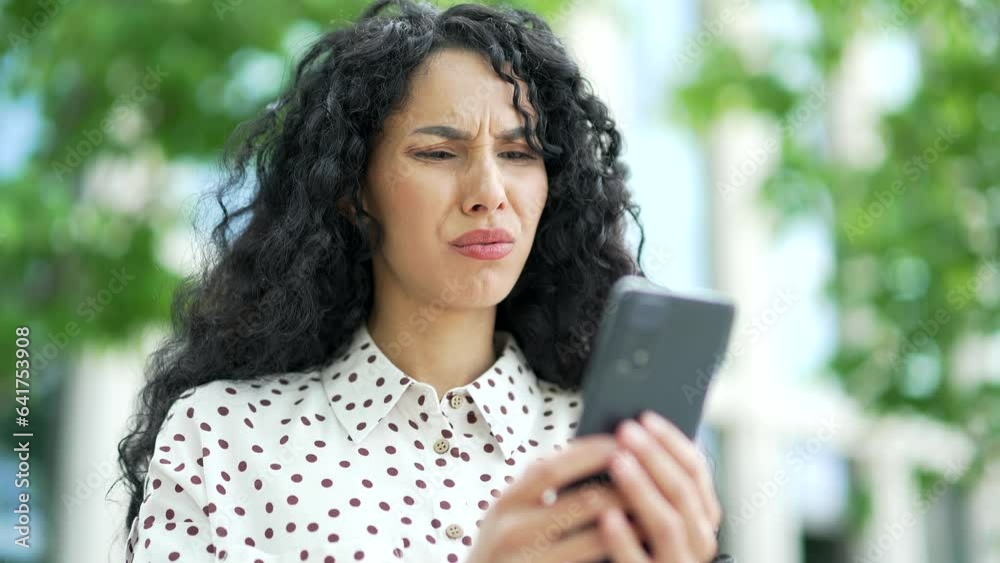Close up. Disappointed young female employee read bad news on smartphone while standing on the street near an office building. Sad shocked woman upset by unpleasant notification, depressed by message Close up. Disappointed young female employee read bad news on smartphone while standing on the street near an office building. Sad shocked woman upset by unpleasant notification, depressed by message