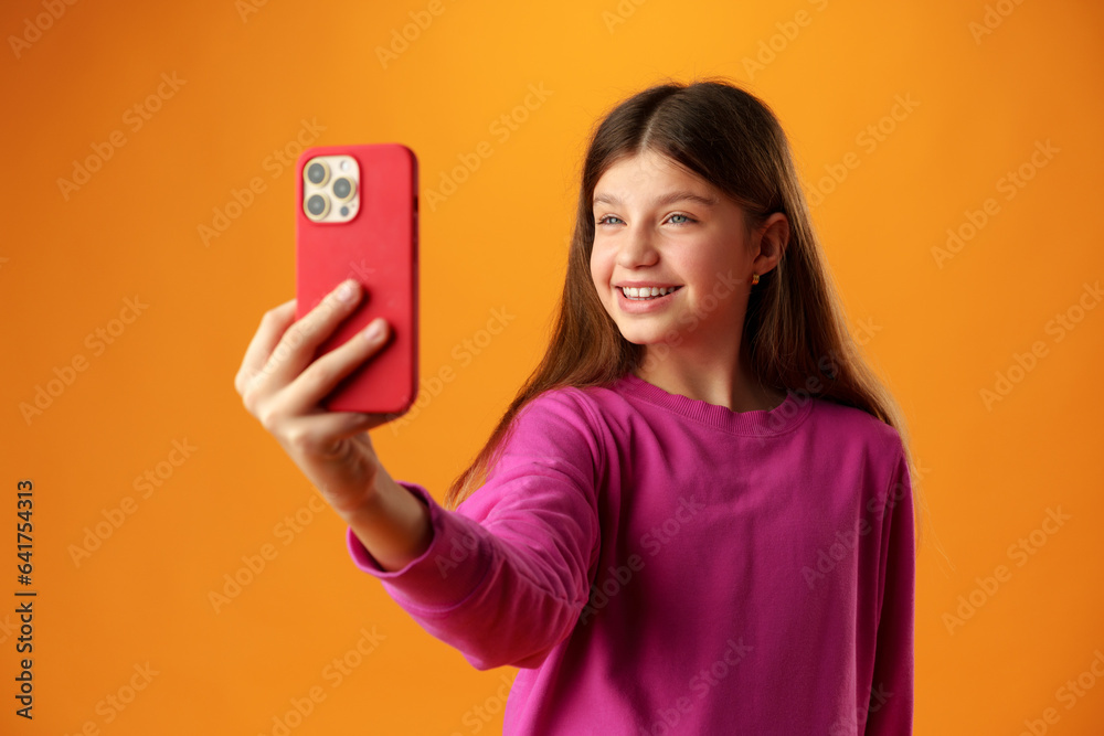 Stylish teen girl using smartphone over yellow background in studio Stylish teen girl using smartphone over yellow background in studio