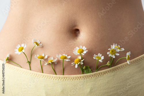 Tableau sur toile Young woman with daisies near the body, intimate hygiene and health
