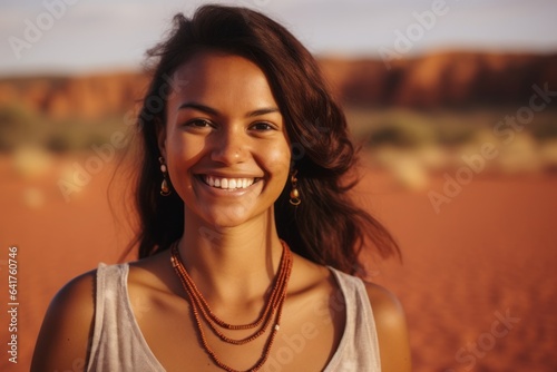 Close-up portrait photography of a cheerful girl in her 30s wearing a chic pearl necklace near the uluru (ayers rock) in northern territory australia. With generative AI technology photo