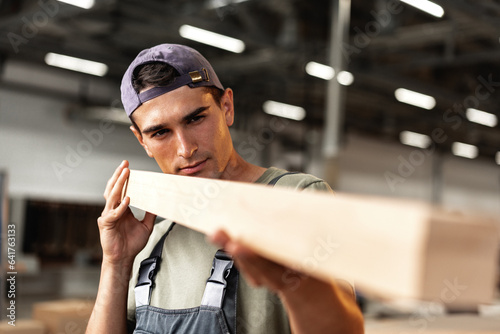 Young carpenter man looking and choosing wood plank at workshop in carpenter wood factory