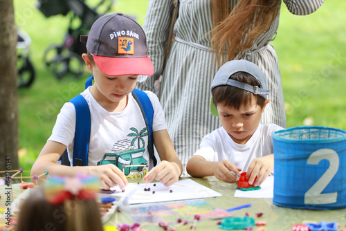 Children paper crafting in outdoor children party, painting, molding of plasticine and making figures cut from paper. Children hobby paper craft modeling, group development of children