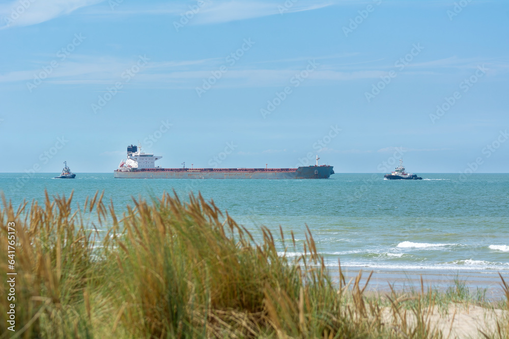 Navire de commerce arrivant près du port de Dunkerque en mer du Nord et pris en charge par plusieurs remorqueurs