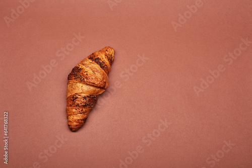 Croissant isolated on the bright solid fond plain red-brown background