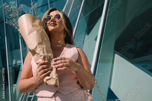 Striking Confidence: Model in Pink Dress and Sunglasses Amid Blue Windows