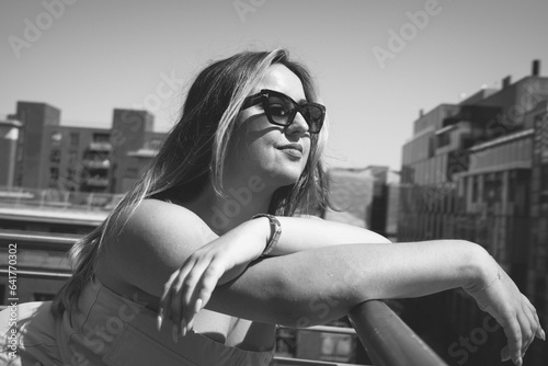 Cityscape Chic: B&W Rooftop Capture of Fashionable Curvy Young Model in Sunglasses