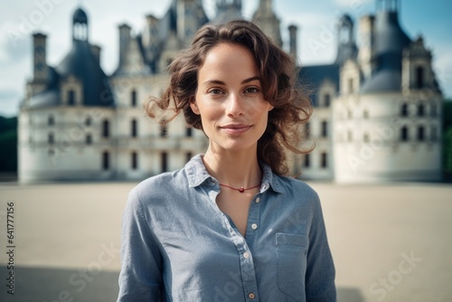 Photography in the style of pensive portraiture of a grinning girl in her 30s wearing a technical climbing shirt at the chateau de chambord in chambord france. With generative AI technology photo