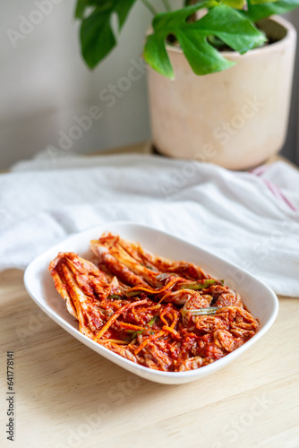 Cabbage Kimchi, a traditional Korean dish made of fermented cabbage or radish, with various seasonings, such as chili powder, garlic, ginger, and fish sauce, in a white plate.