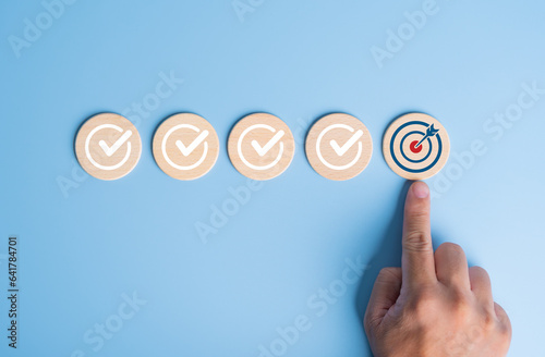 Checklist, Mission plan, Task list, Survey review, Quality control, Goals achievement, and Business success. To-do list for achieving targets. Hand point on target dartboard icons on wooden circles. photo