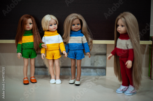 Several toy dolls are watching another one to the side.