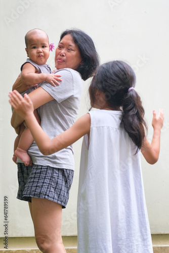 A mother playing with her daughter and baby boy photo