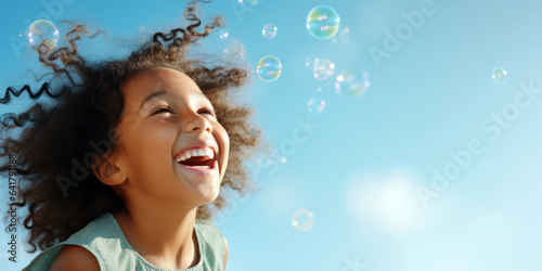 happy mixed-race girl, bubbles, against a sky-blue background, room for copyspace 