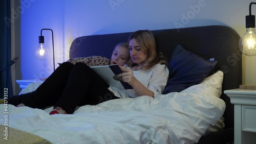 young mother reading a book to children
