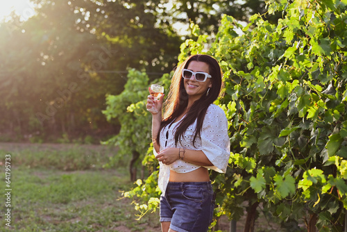 Young beautiful Smiling italian woman walking at wineyard with a Glass of Red wine.Wine tourism at Tuscany,Italy