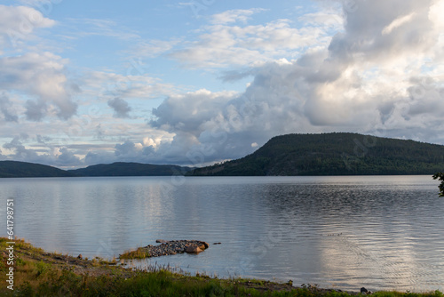 Lake with mountains in the distance and big white clouds in the blue sky
